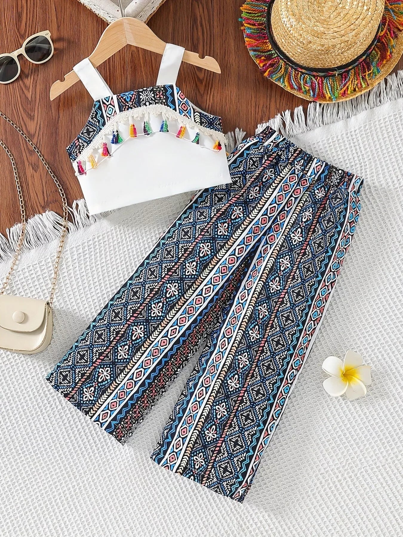 Children’s two-piece boho outfit with tassel crop top, printed wide-leg pants, pockets, and colorful summer styling.