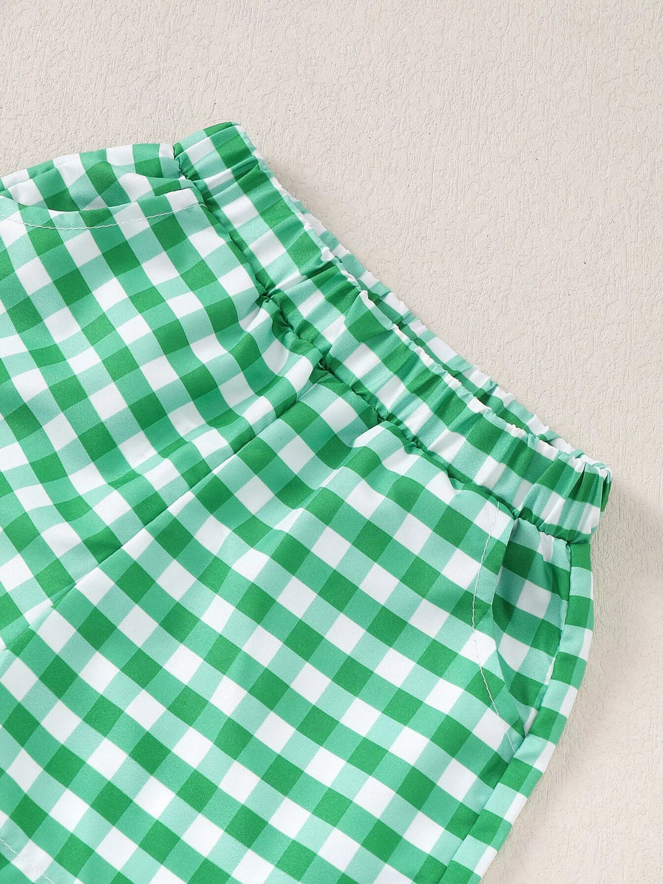Two-piece baby outfit with blue turtle appliqué T-shirt and green gingham shorts made from a soft cotton-blend fabric.