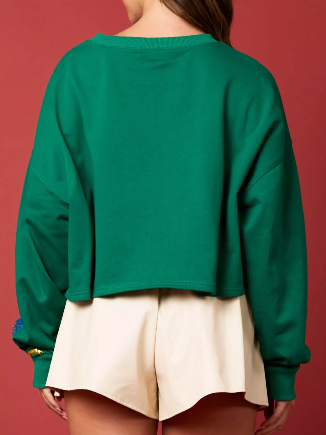 Woman wearing a green sweatshirt decorated with colorful sequin Christmas lights — festive holiday top from A Whimsical Affair.