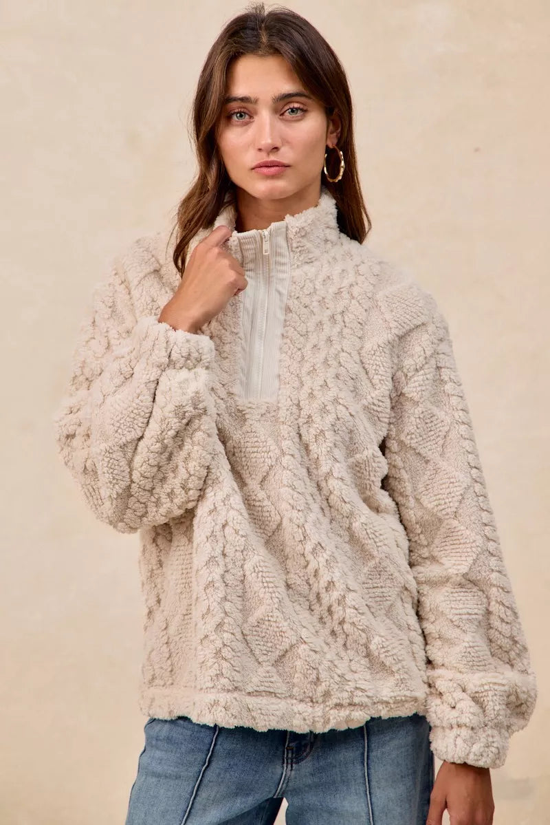 Model wearing the Vanilla Frost Cable Fleece Pullover — a cream-colored, cable-textured fleece half-zip sweater with a relaxed, cozy fit.