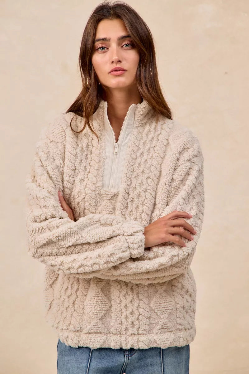 Model wearing the Vanilla Frost Cable Fleece Pullover — a cream-colored, cable-textured fleece half-zip sweater with a relaxed, cozy fit.