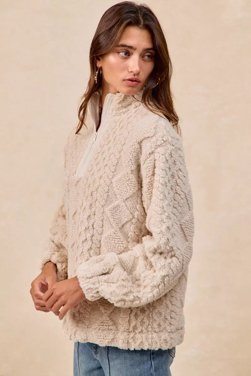 Model wearing the Vanilla Frost Cable Fleece Pullover — a cream-colored, cable-textured fleece half-zip sweater with a relaxed, cozy fit.