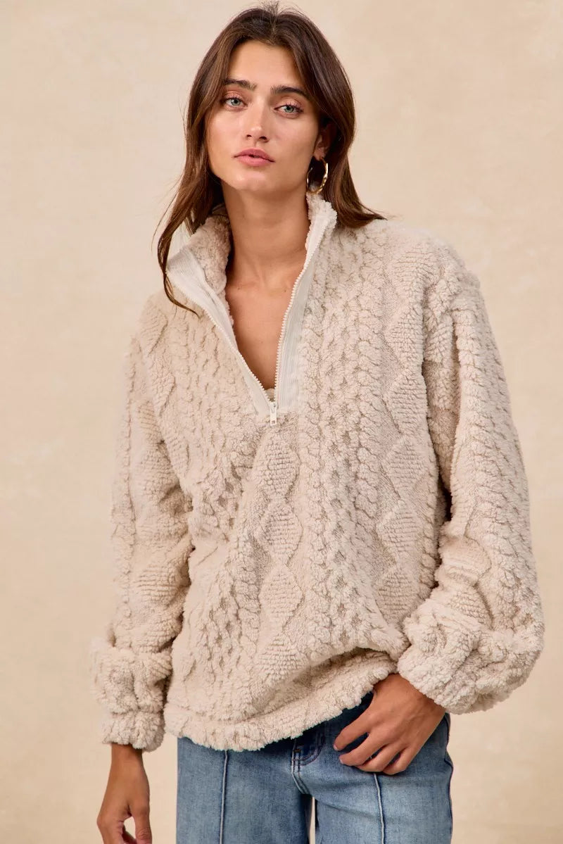 Model wearing the Vanilla Frost Cable Fleece Pullover — a cream-colored, cable-textured fleece half-zip sweater with a relaxed, cozy fit.