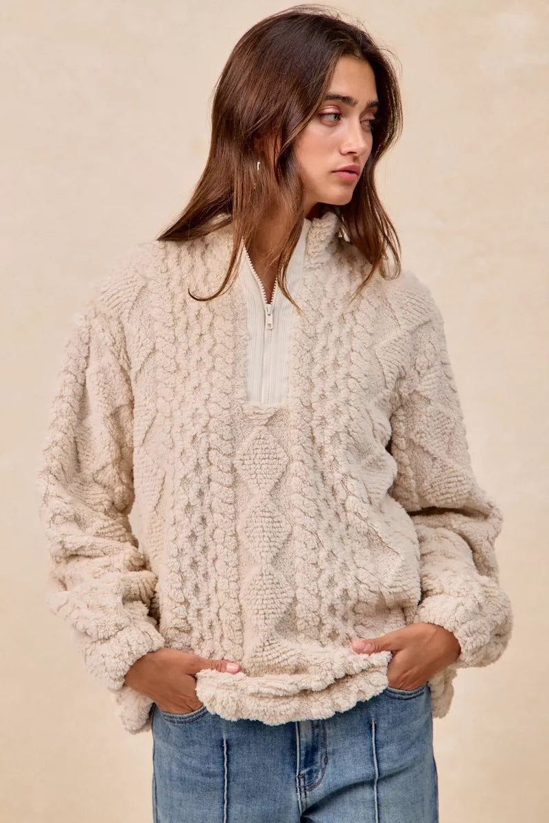 Model wearing the Vanilla Frost Cable Fleece Pullover — a cream-colored, cable-textured fleece half-zip sweater with a relaxed, cozy fit.
