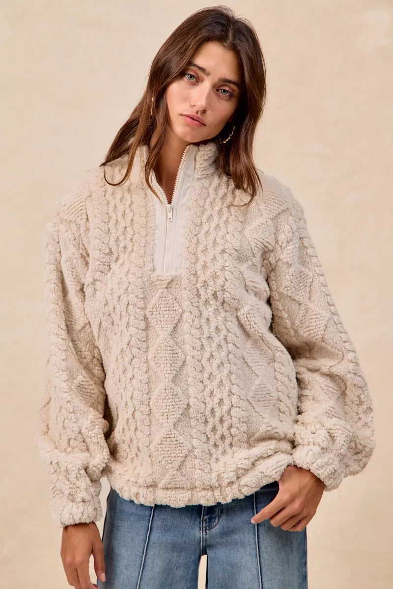 Model wearing the Vanilla Frost Cable Fleece Pullover — a cream-colored, cable-textured fleece half-zip sweater with a relaxed, cozy fit.