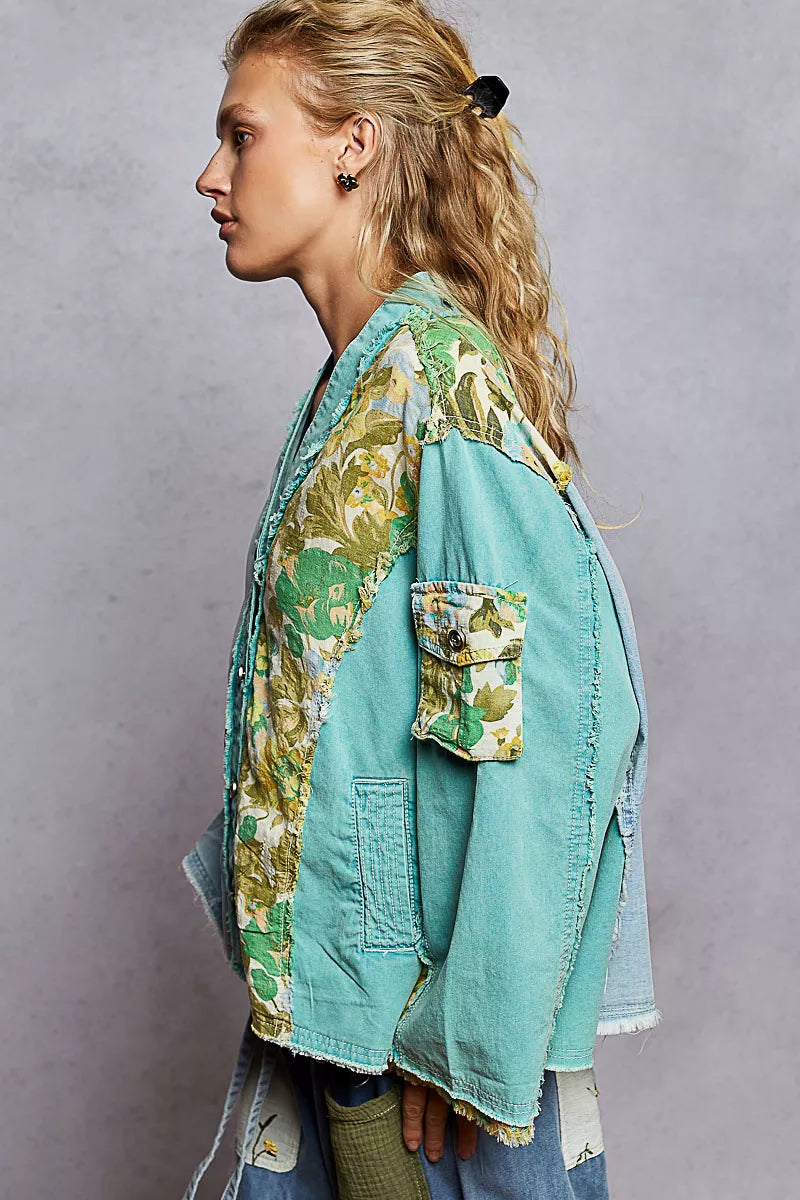 Woman wearing a green and blue patchwork button-up boho top with floral panels and raw frayed edges