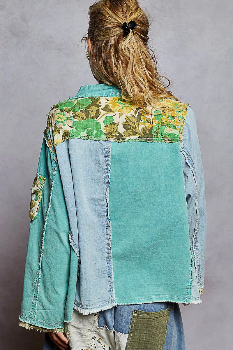 Woman wearing a green and blue patchwork button-up boho top with floral panels and raw frayed edges