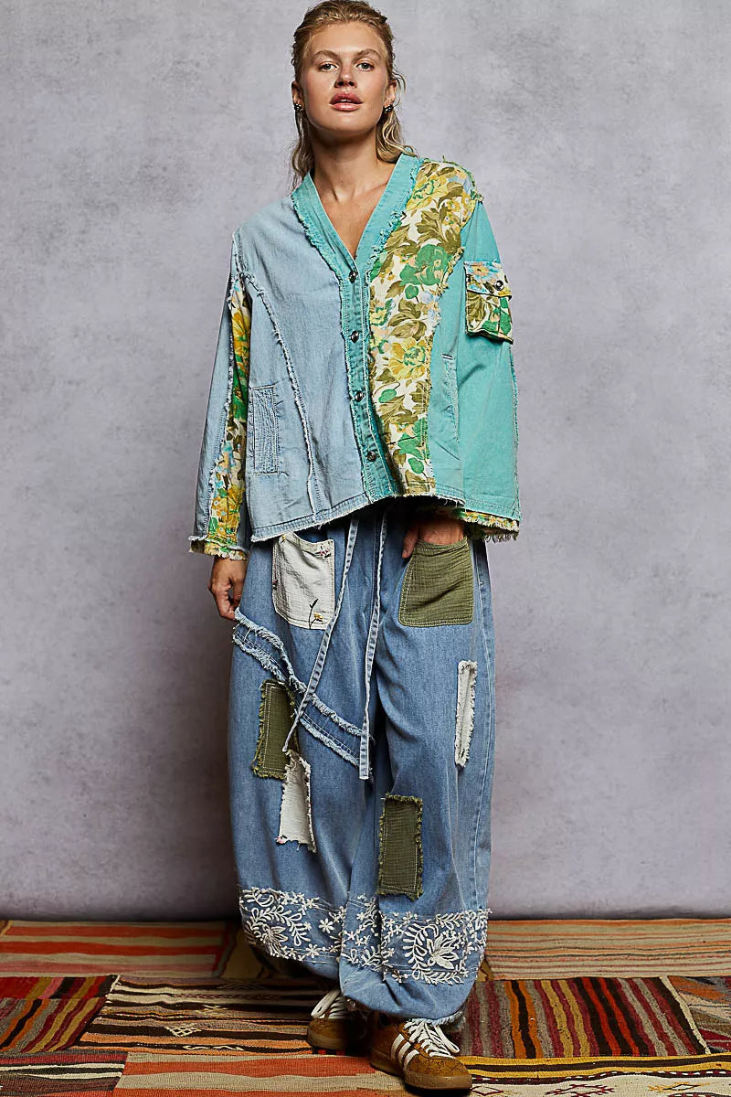 Woman wearing a green and blue patchwork button-up boho top with floral panels and raw frayed edges