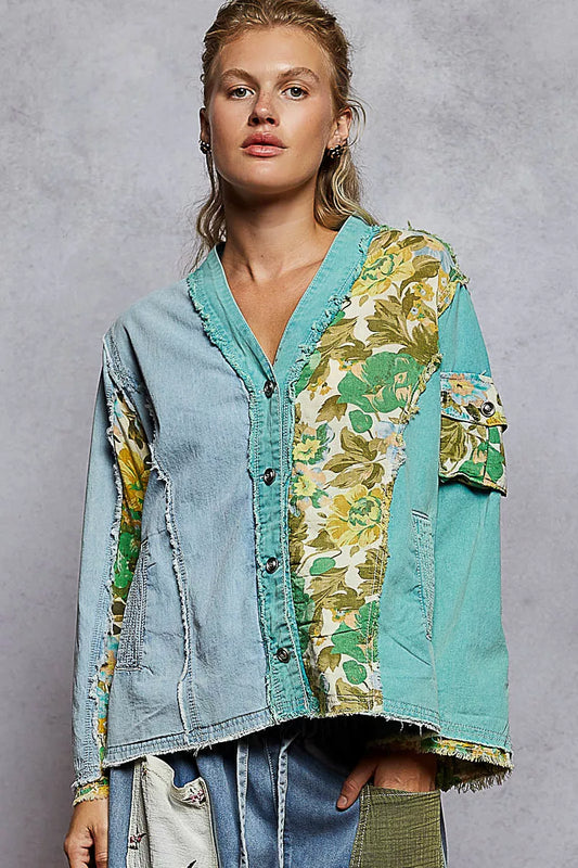 Woman wearing a green and blue patchwork button-up boho top with floral panels and raw frayed edges