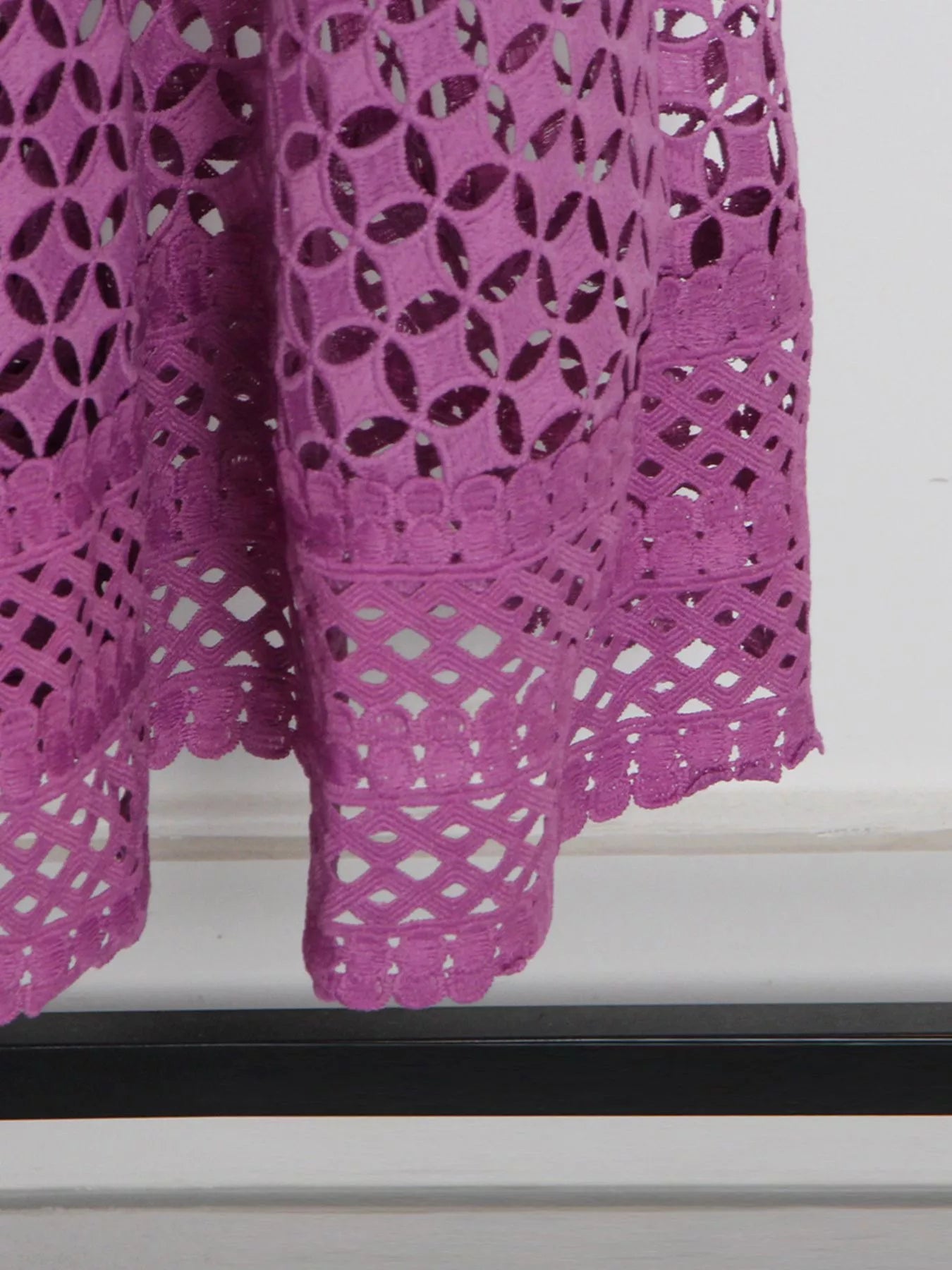 Model wearing the Violet Lace Cutout Midi Dress with long sheer balloon sleeves, high neckline, and geometric lace design, styled with white strappy heels.