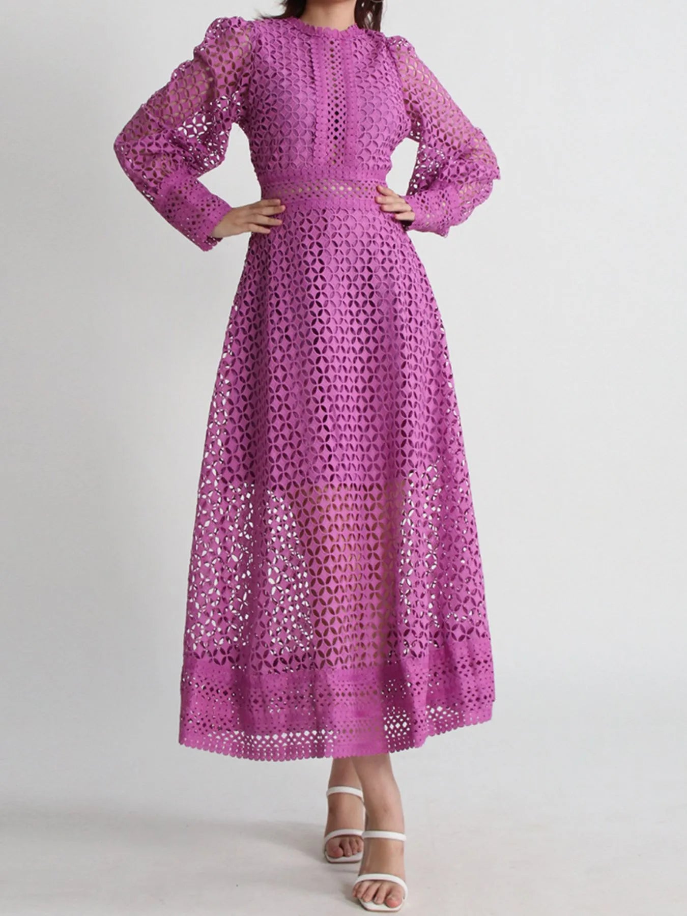 Model wearing the Violet Lace Cutout Midi Dress with long sheer balloon sleeves, high neckline, and geometric lace design, styled with white strappy heels.