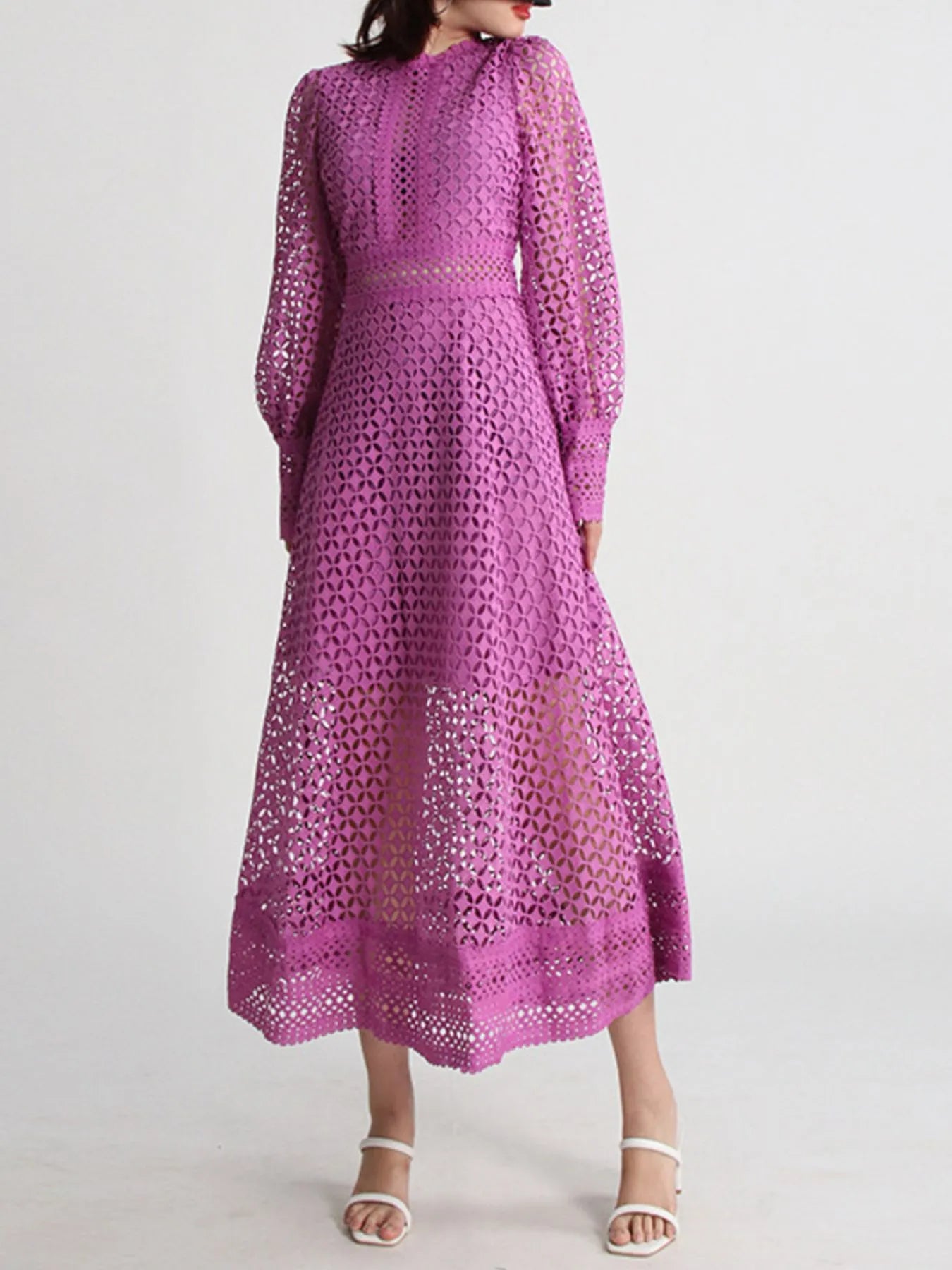 Model wearing the Violet Lace Cutout Midi Dress with long sheer balloon sleeves, high neckline, and geometric lace design, styled with white strappy heels.
