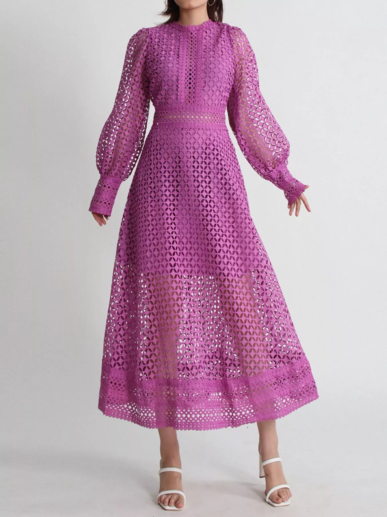 Model wearing the Violet Lace Cutout Midi Dress with long sheer balloon sleeves, high neckline, and geometric lace design, styled with white strappy heels.