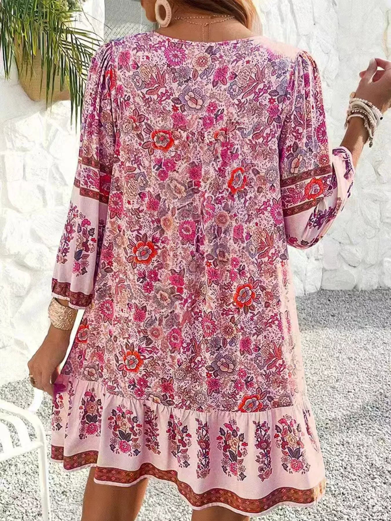 Boho floral tunic dress with long sleeves, a tie neckline, and mixed floral border print.