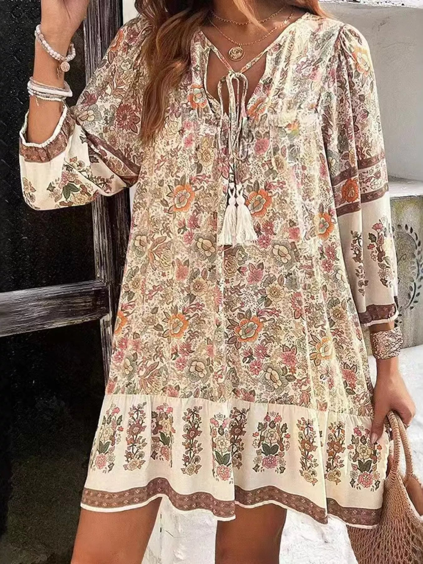 Boho floral tunic dress with long sleeves, a tie neckline, and mixed floral border print.