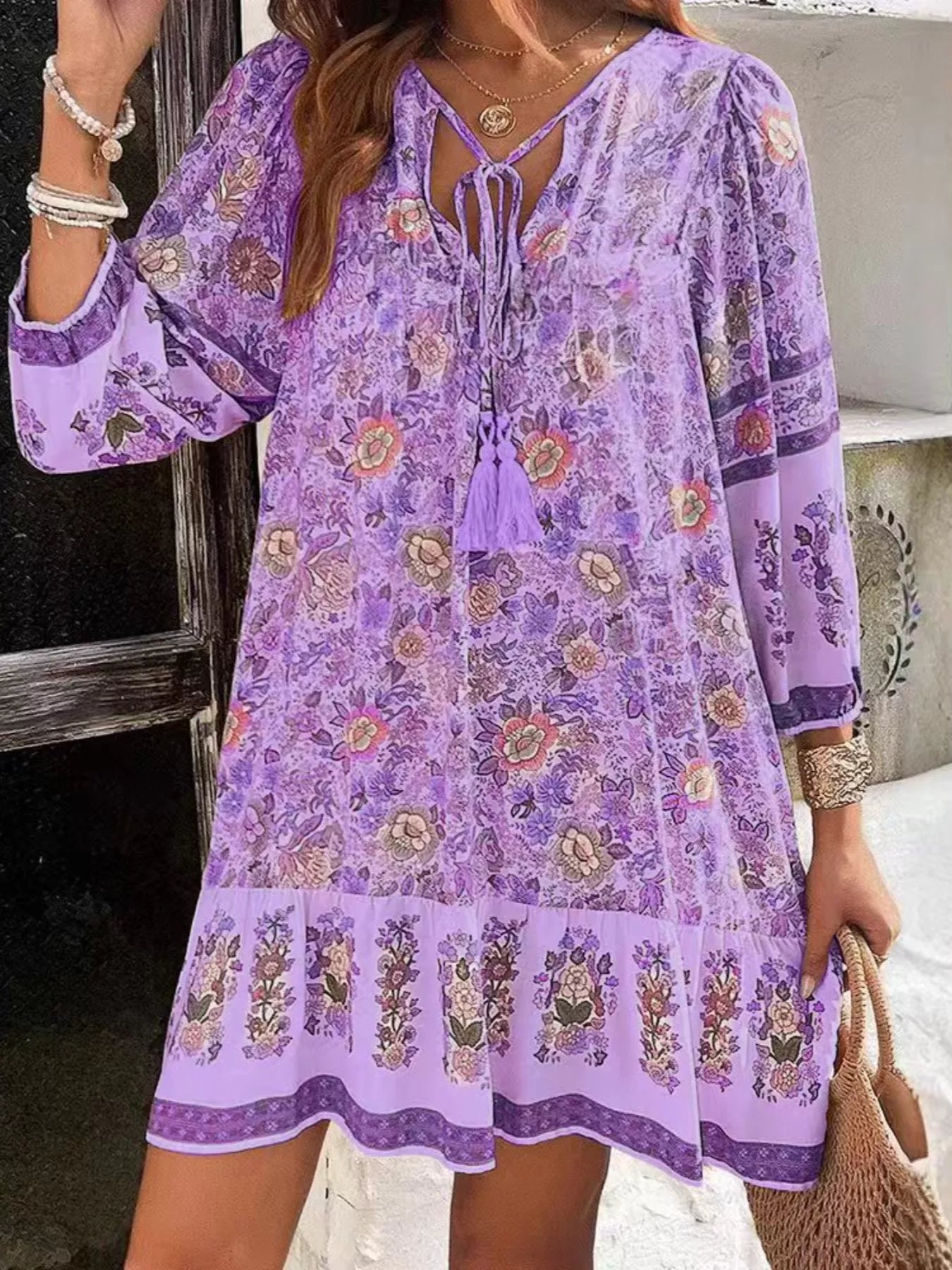 Boho floral tunic dress with long sleeves, a tie neckline, and mixed floral border print.
