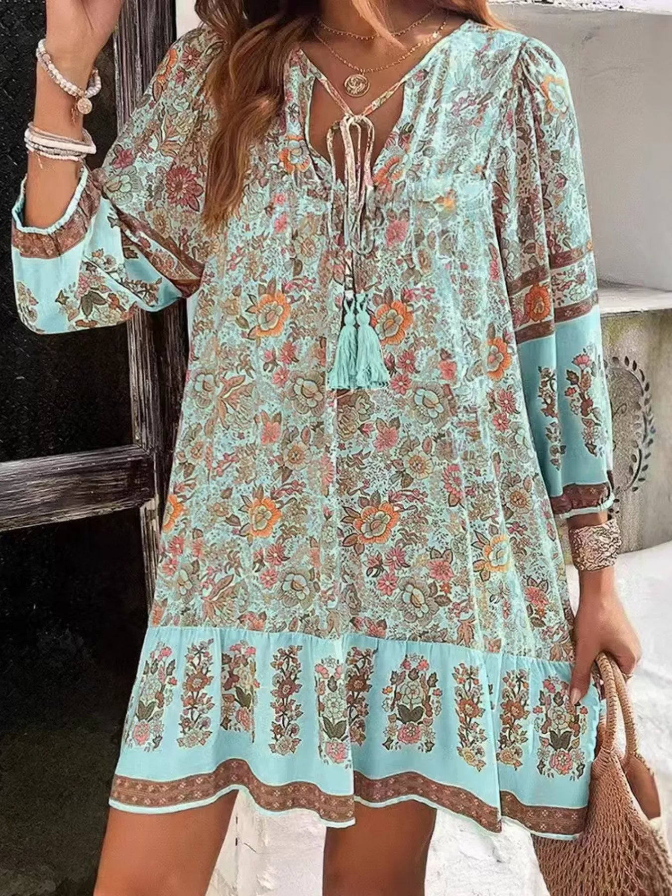 Boho floral tunic dress with long sleeves, a tie neckline, and mixed floral border print.