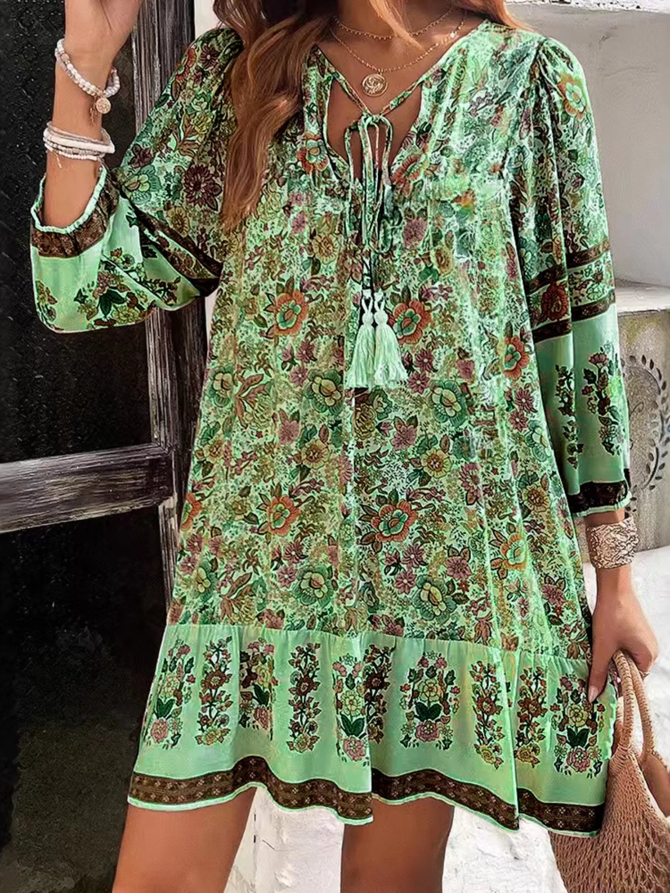 Boho floral tunic dress with long sleeves, a tie neckline, and mixed floral border print.