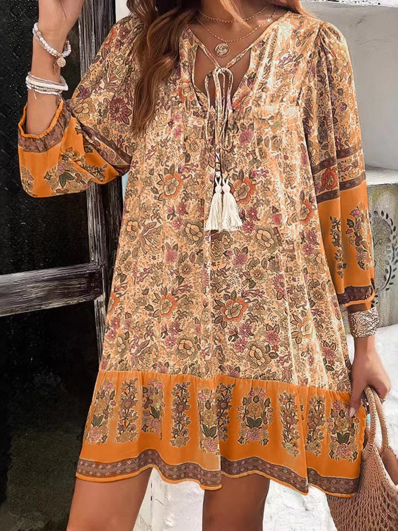 Boho floral tunic dress with long sleeves, a tie neckline, and mixed floral border print.