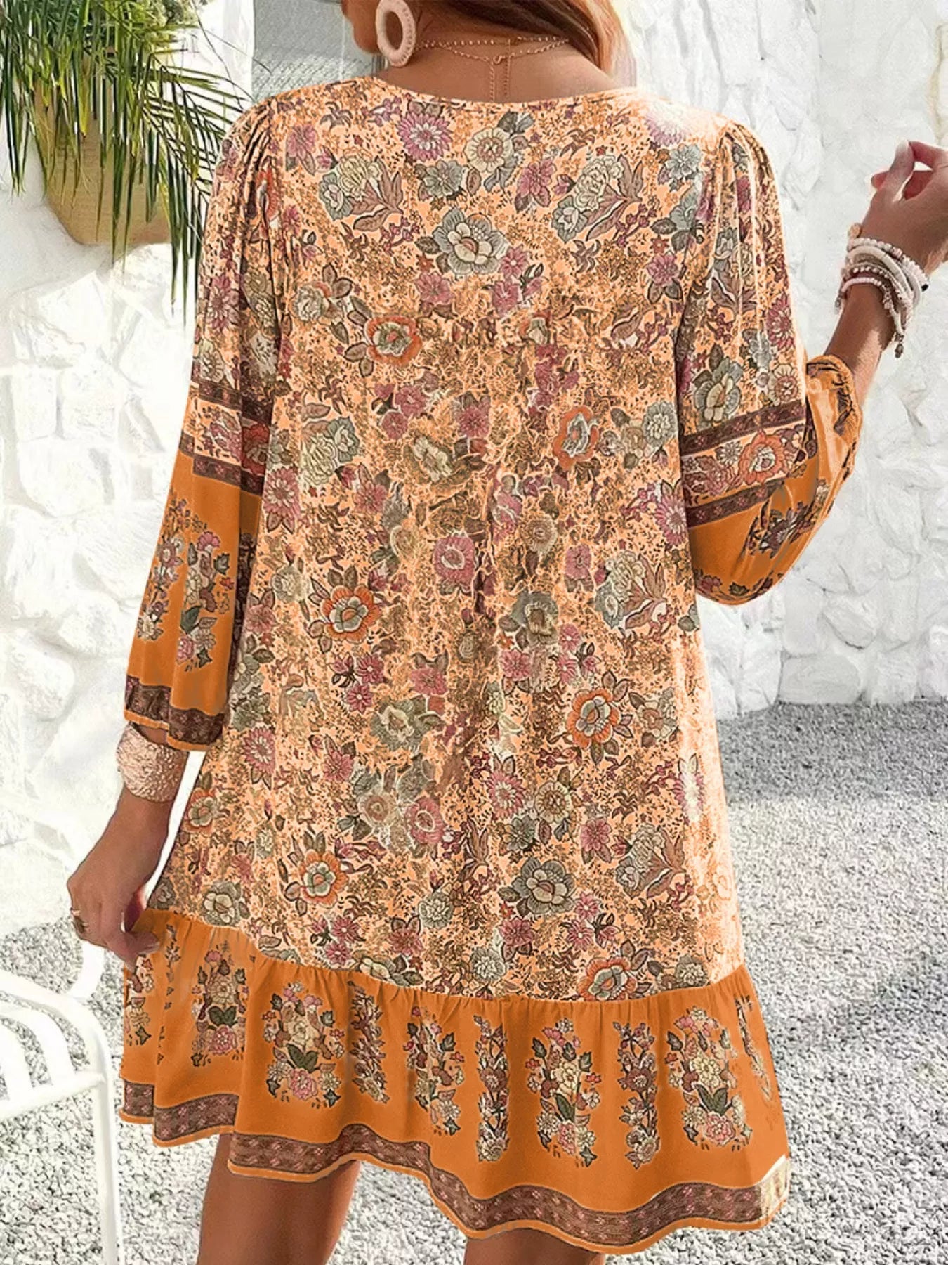 Boho floral tunic dress with long sleeves, a tie neckline, and mixed floral border print.