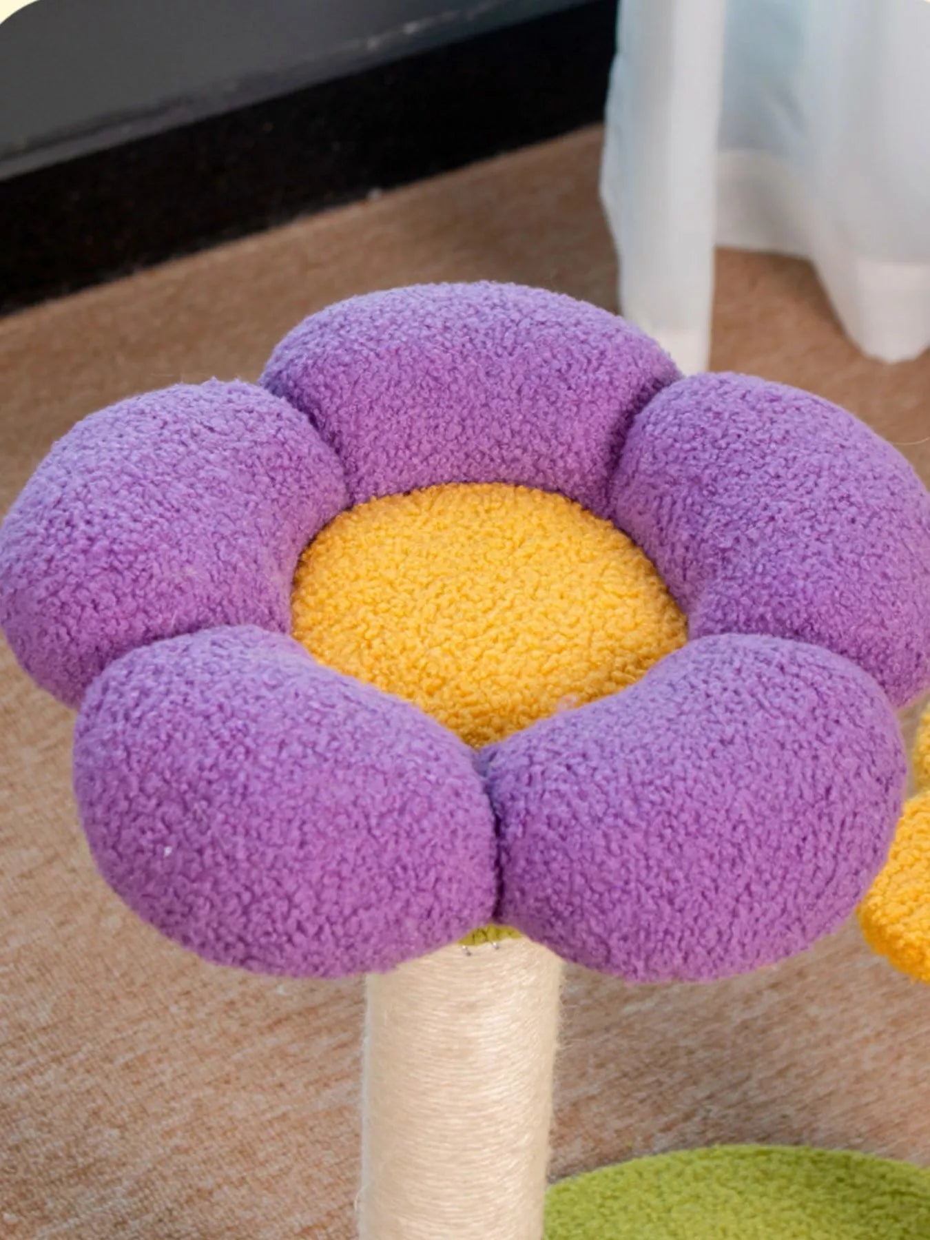 White cat lounging on colorful flower-shaped cat perch with scratching post