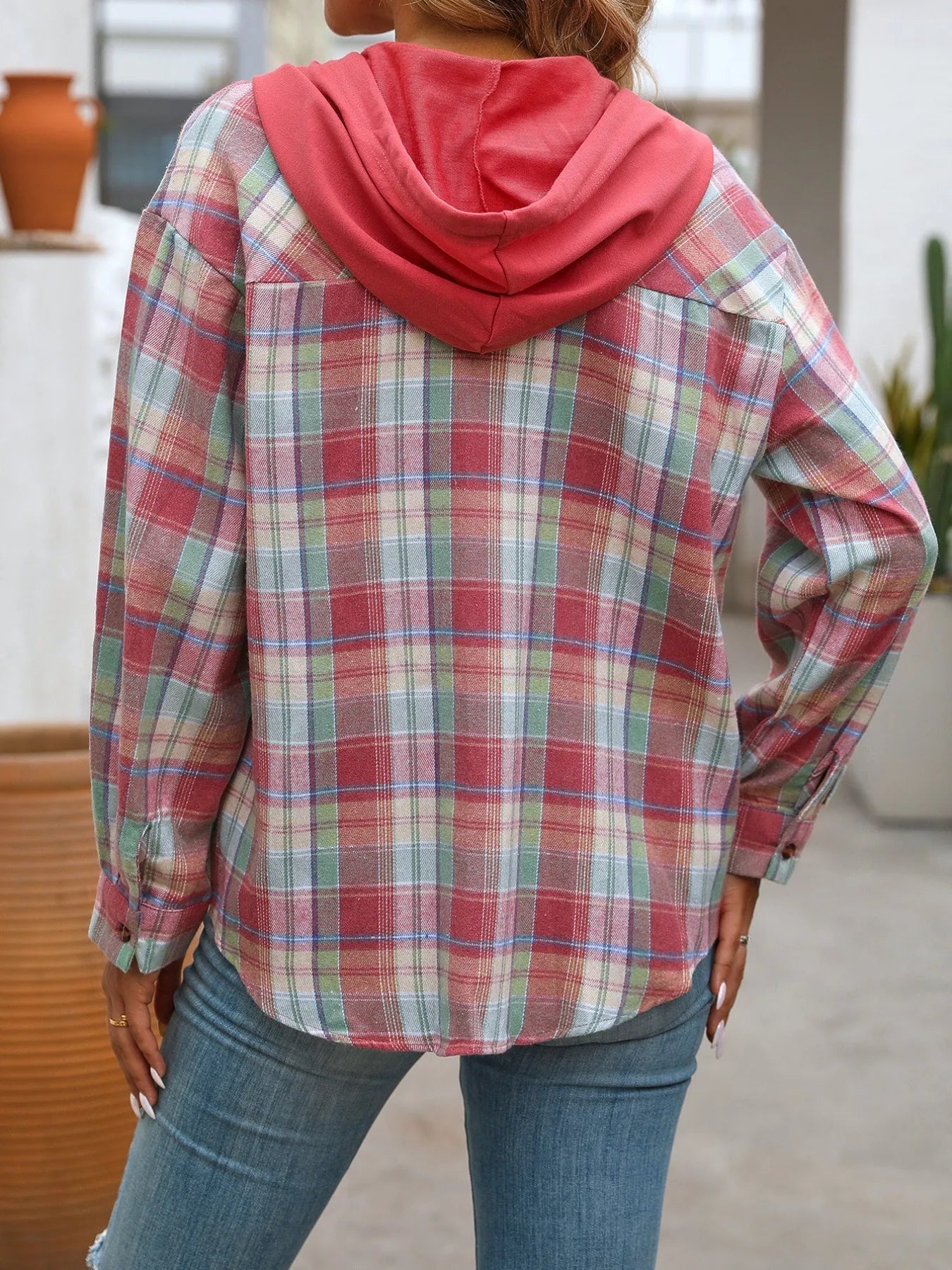 Close-up of woman wearing a red plaid hoodie shirt with front buttons and pocket, styled with jeans for a cozy autumn outfit.