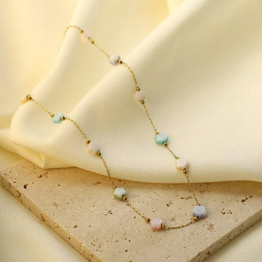 Delicate gold plated beaded chain necklace with soft resin beads displayed on a neutral fabric background