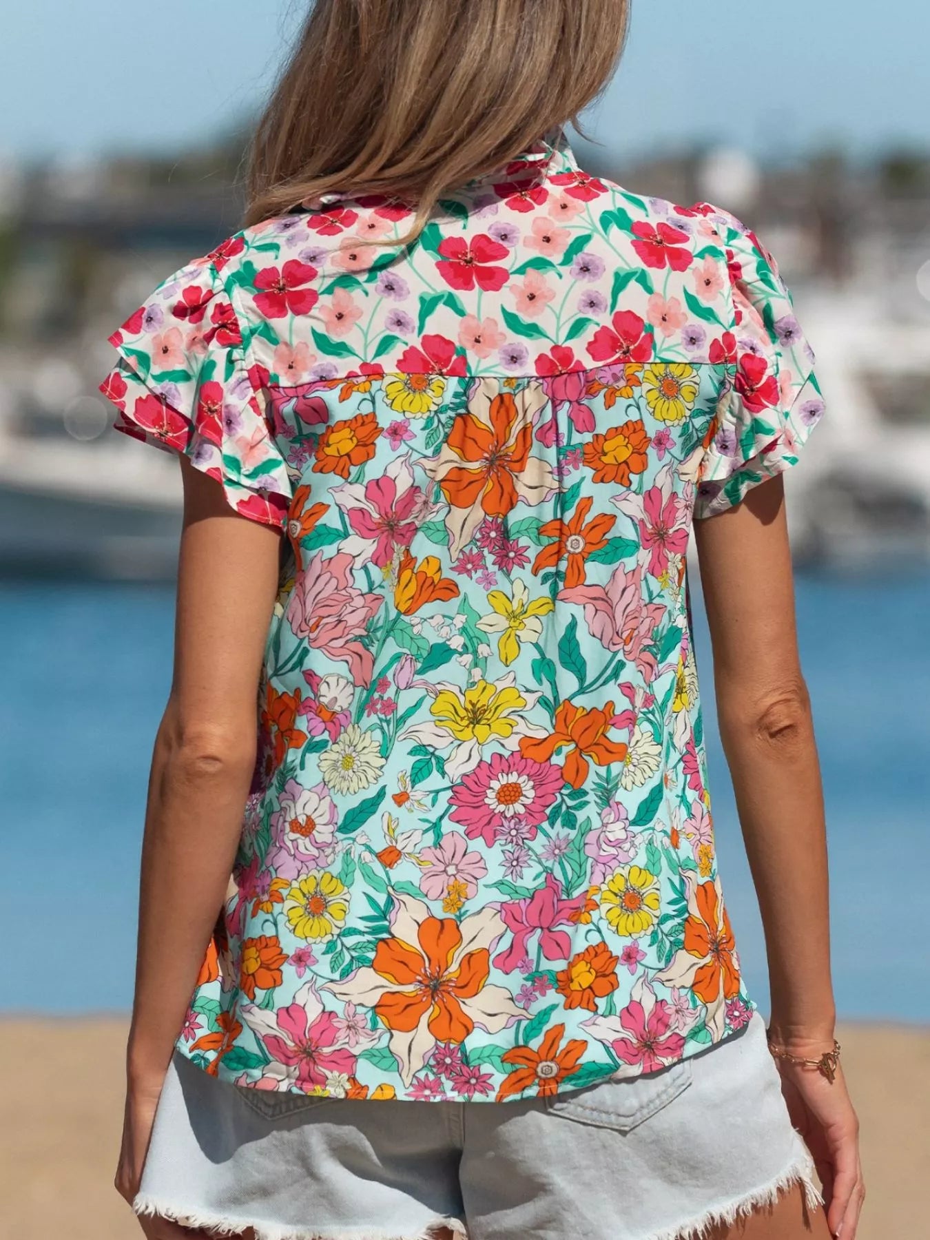 colorful floral boho blouse with ruffle sleeves and relaxed fit paired with distressed denim shorts