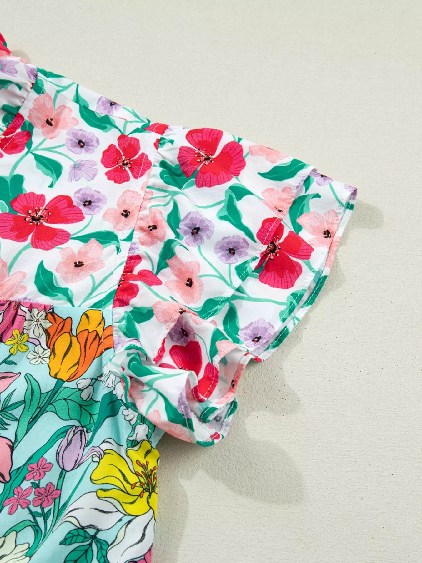 colorful floral boho blouse with ruffle sleeves and relaxed fit paired with distressed denim shorts