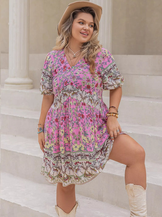 Woman wearing a pink floral plus size mini dress with short puff sleeves, styled with a cowgirl hat and boots.