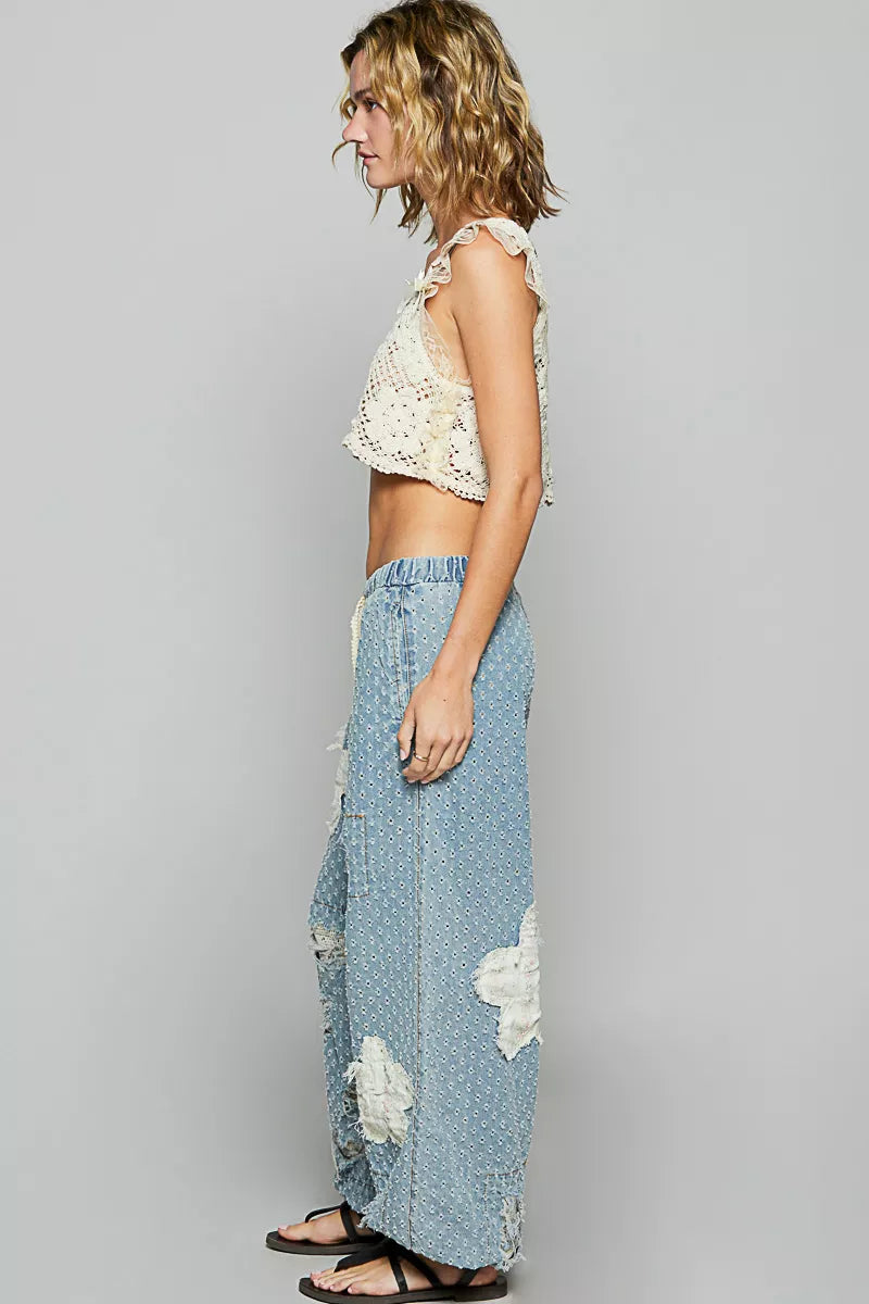 Vintage-washed blue joggers with floral appliqué patches, crochet distressing, and drawstring waist.