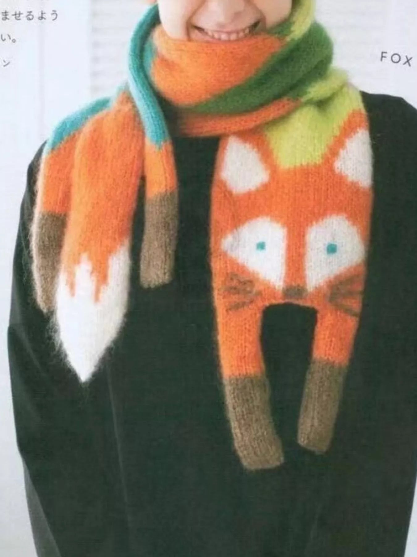 Whimsical knit fox scarf with soft texture and tapered ends hanging on a wooden branch.