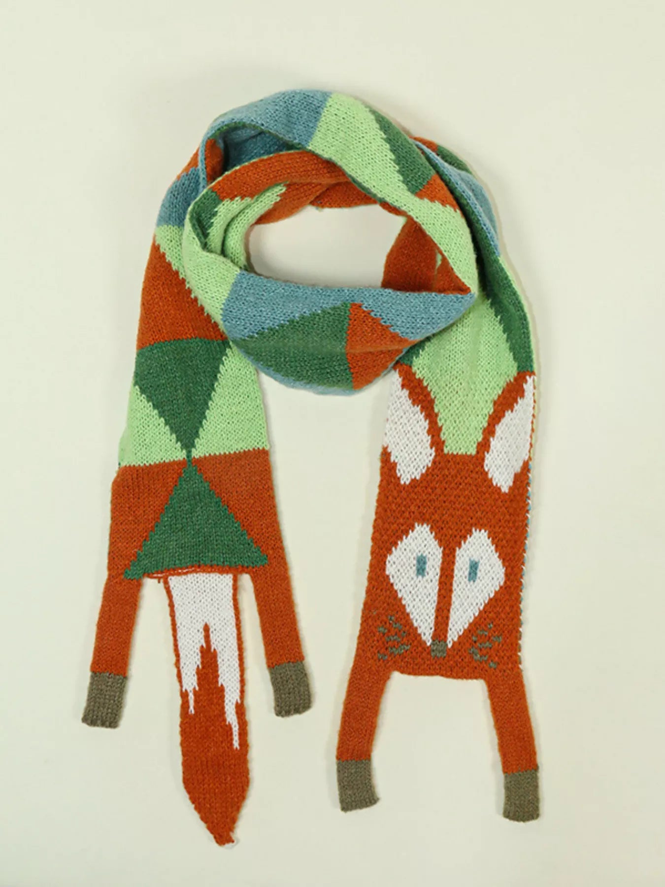 Whimsical knit fox scarf with soft texture and tapered ends hanging on a wooden branch.