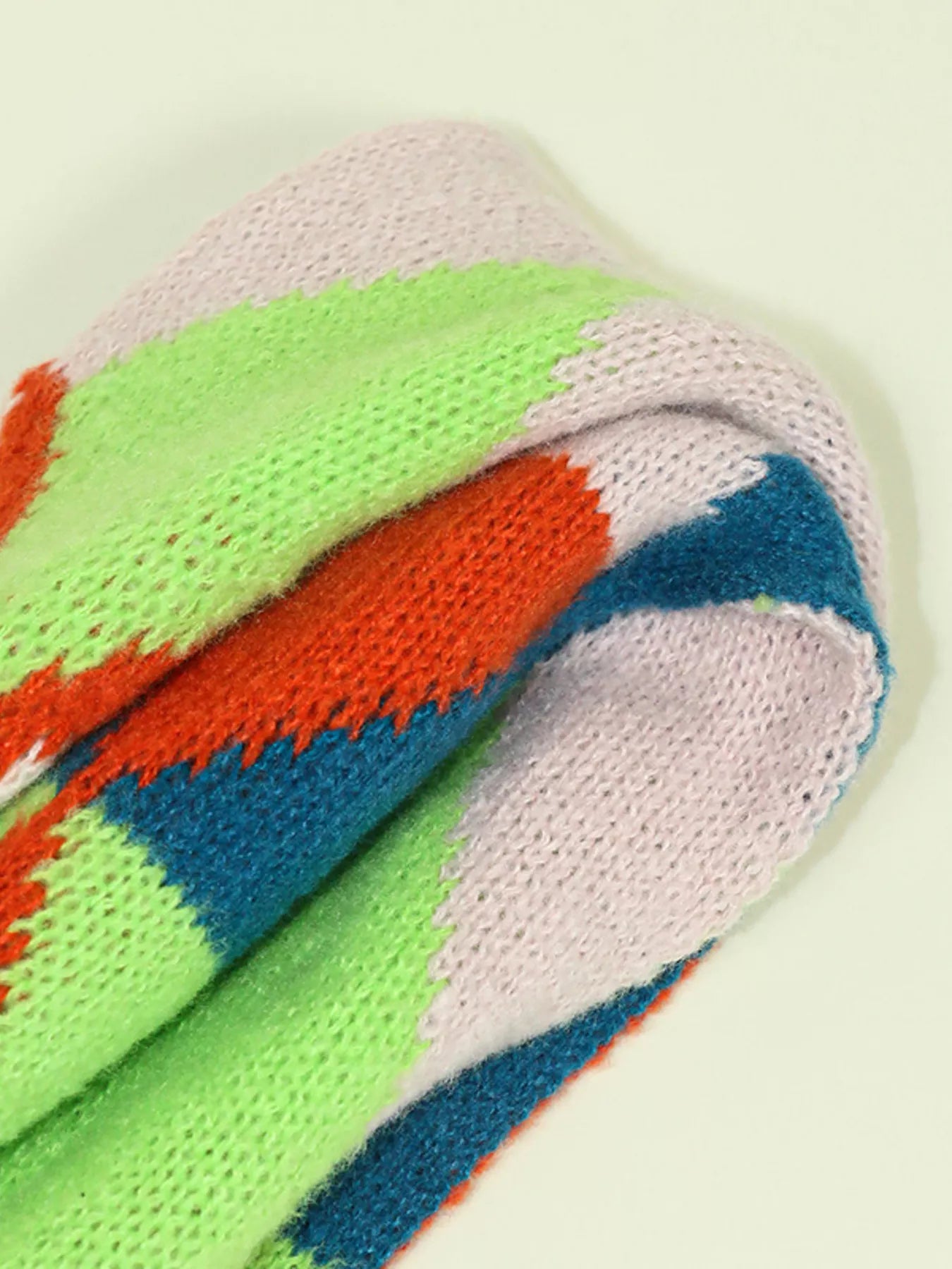 Whimsical knit fox scarf with soft texture and tapered ends hanging on a wooden branch.