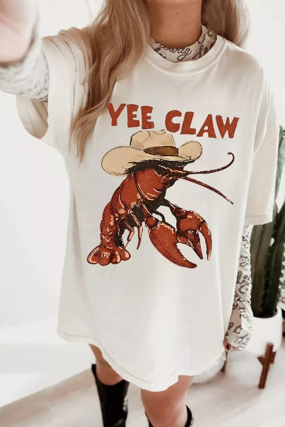 White oversized graphic tee with cowboy lobster and Yee Claw print