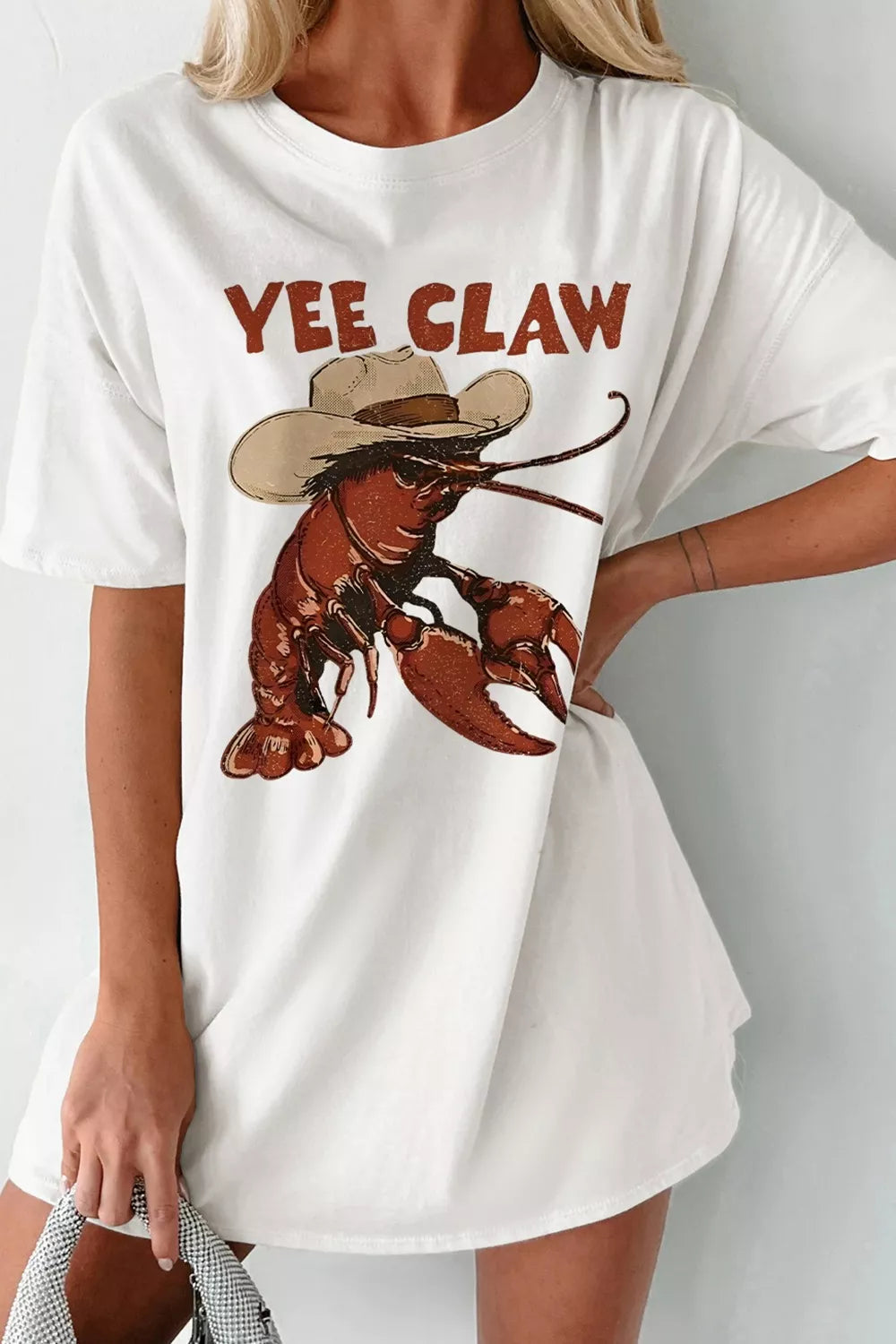 White oversized graphic tee with cowboy lobster and Yee Claw print